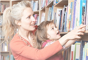 Young woman helping a child pick out a book at the library