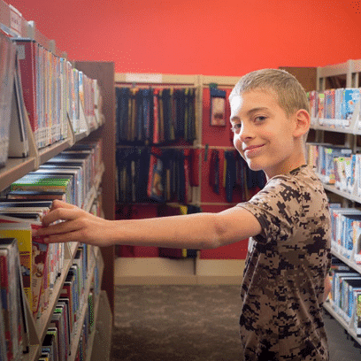Boy picking a book out off the shelf at the Hussey-Mayfield library