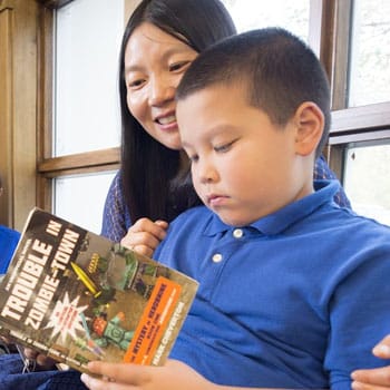 A male child reading 'Trouble in Zombie-Town'