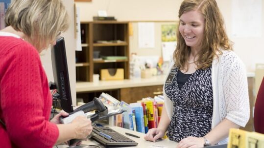 Woman checking out a book from the library with her card