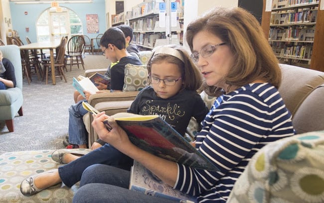 A member of the library foundation reading to a young girl in the Zionsville library