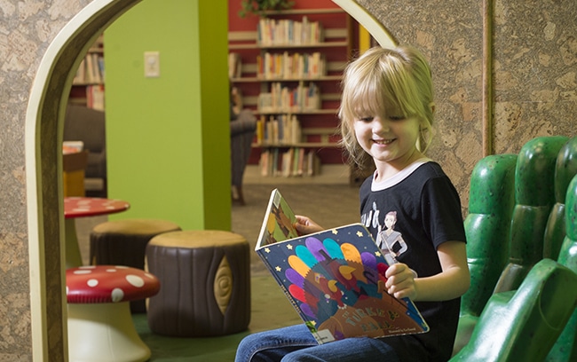 Young girl reading a book in play room.