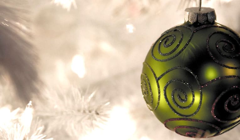 Green Christmas ornament hanging on a white Christmas tree