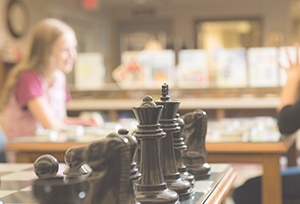 Image of chess board with kids sitting in the background