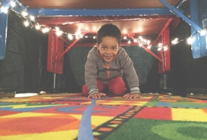 Toddler boy crawling on the carpet in a play room