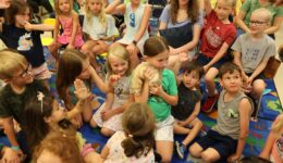 Children and caregivers watching a girl hold a ferret