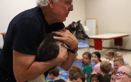 Children and caregivers watching a man with an arctic fox