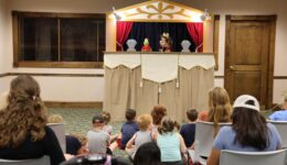 Audience of children and caregivers watching puppet show