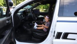 Young girl sitting in driver seat of police cruiser