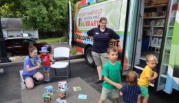 Woman reading to young child and children getting on Bookmobile
