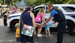 Police officer handing sticker to children with caregiver