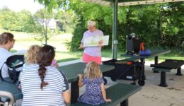 Librarian reading a story to caregivers and children at the park