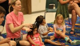 Children and caregivers listening to ASL storytime and practicing ASL signs