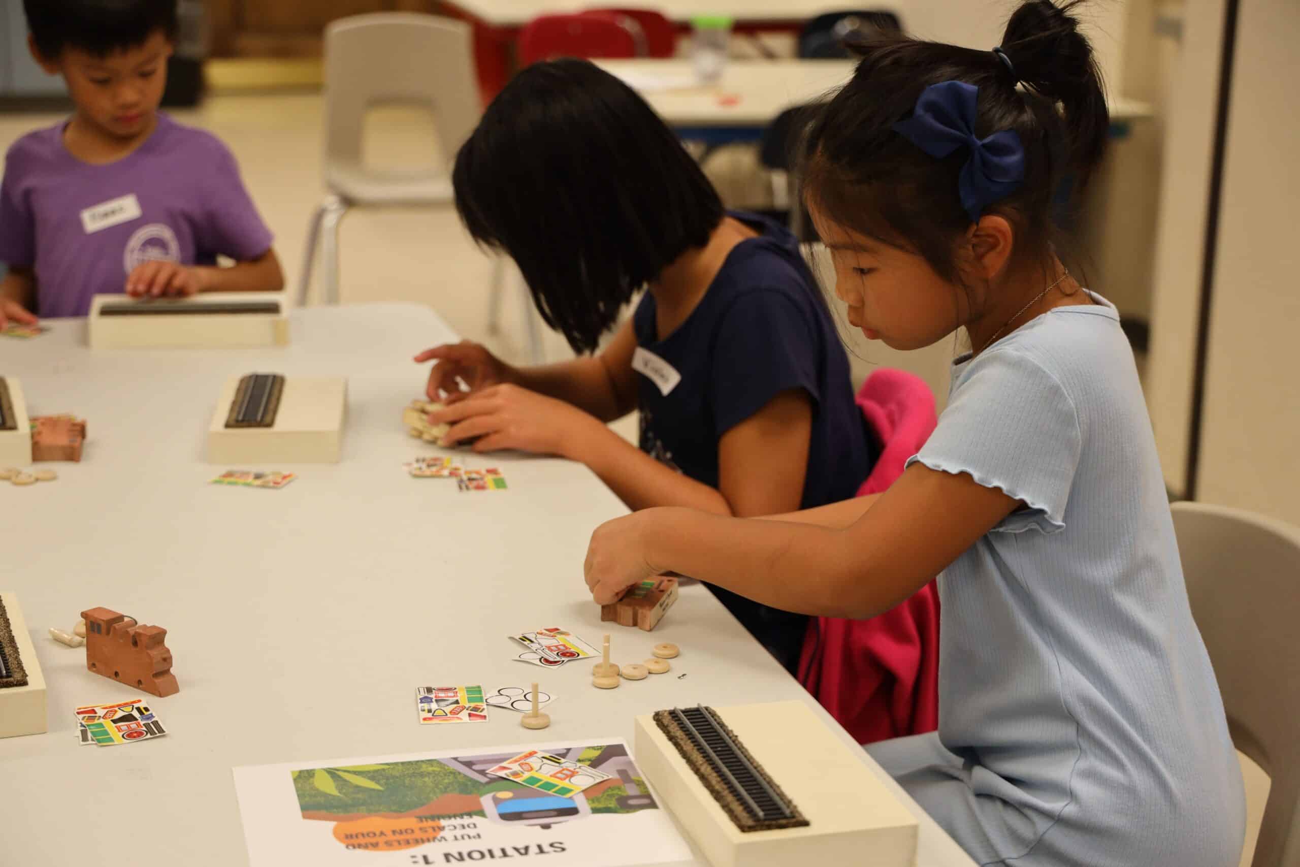 Children, caregivers and librarians work on a train craft