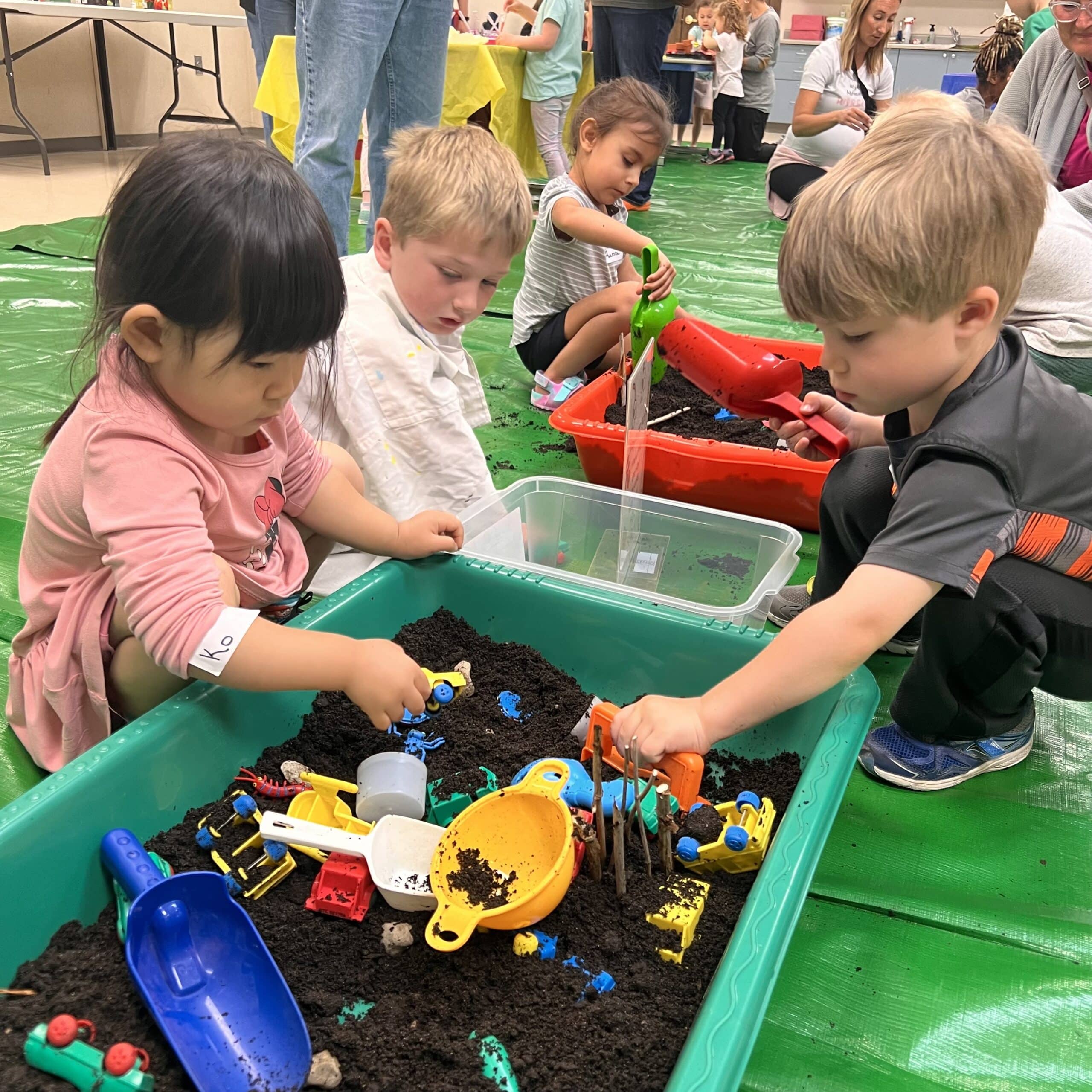 Children playing with toys in dirt sensory bins
