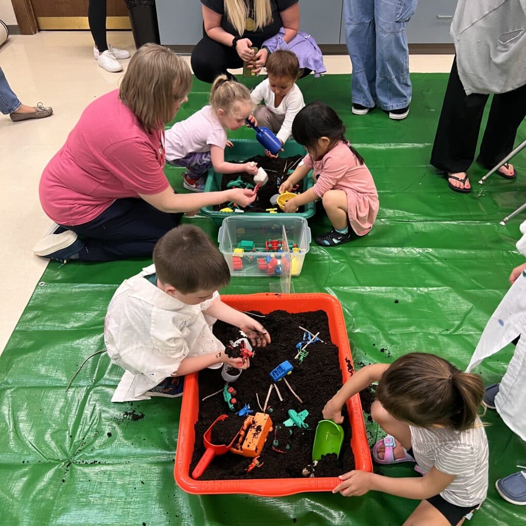 Children playing with toys in dirt sensory bins
