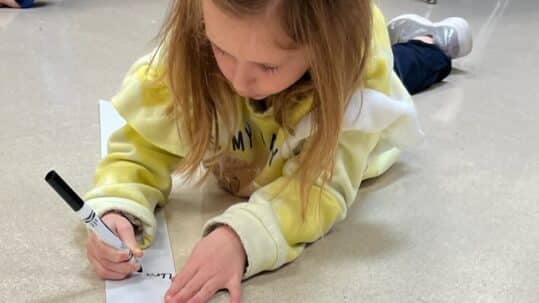 Child writing on a long strip of paper