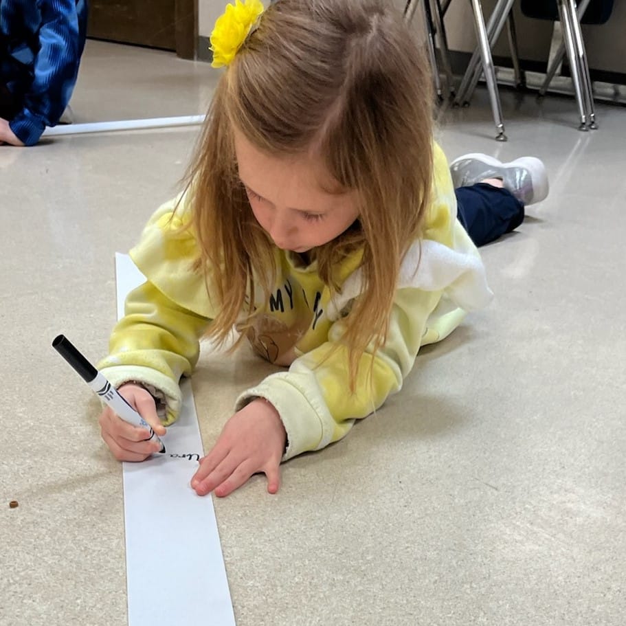 Child writing on a long strip of paper