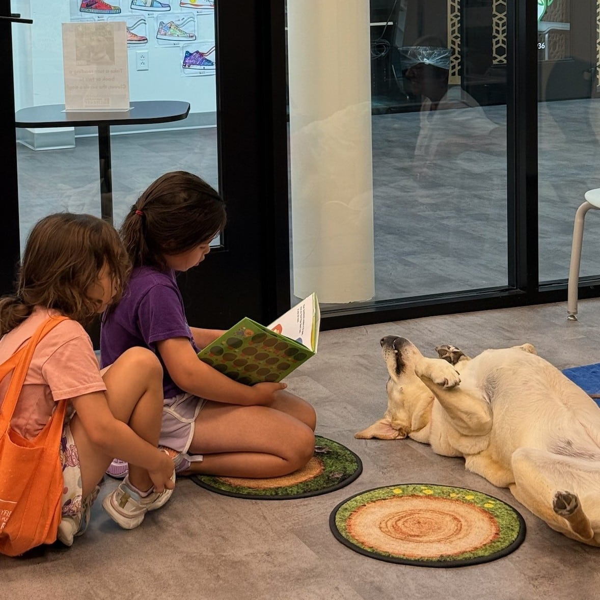 Two children reading to a dog