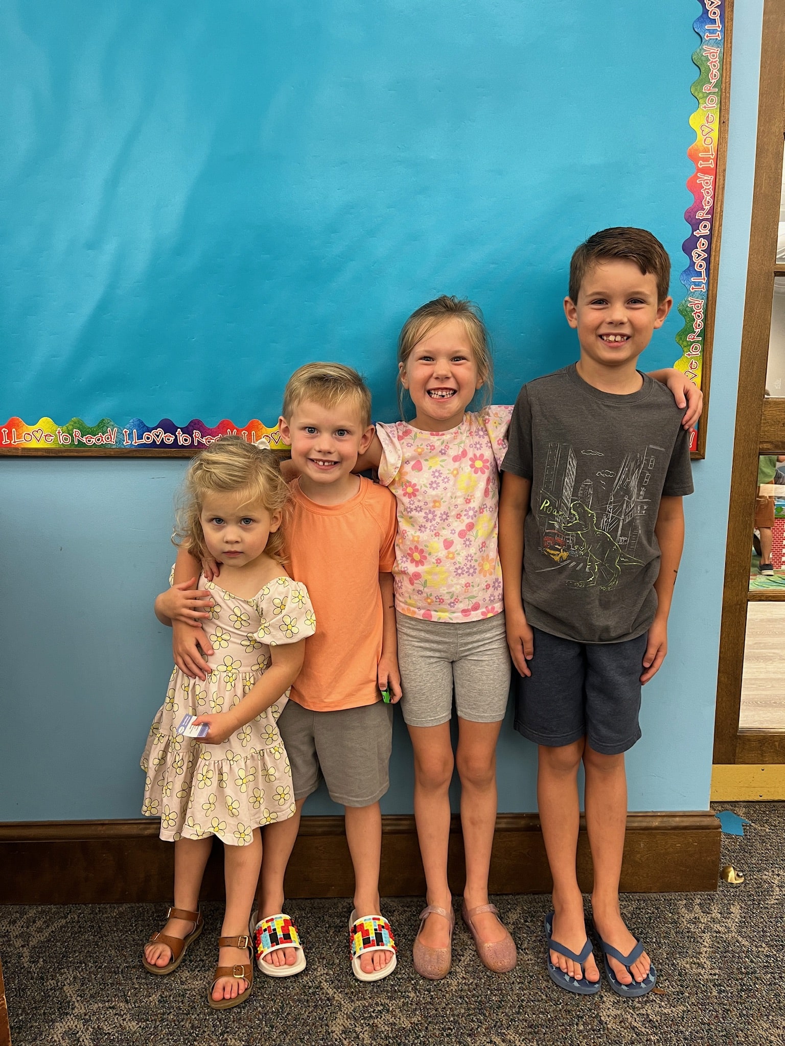 four siblings in front of bulletin board